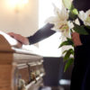 woman with lily flowers and coffin at funeral